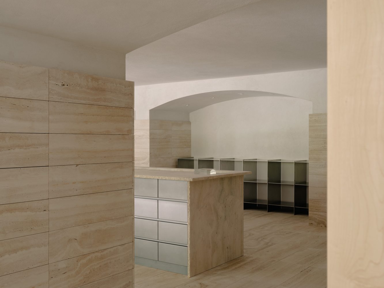 Travertine counter with steel drawers beneath an arch