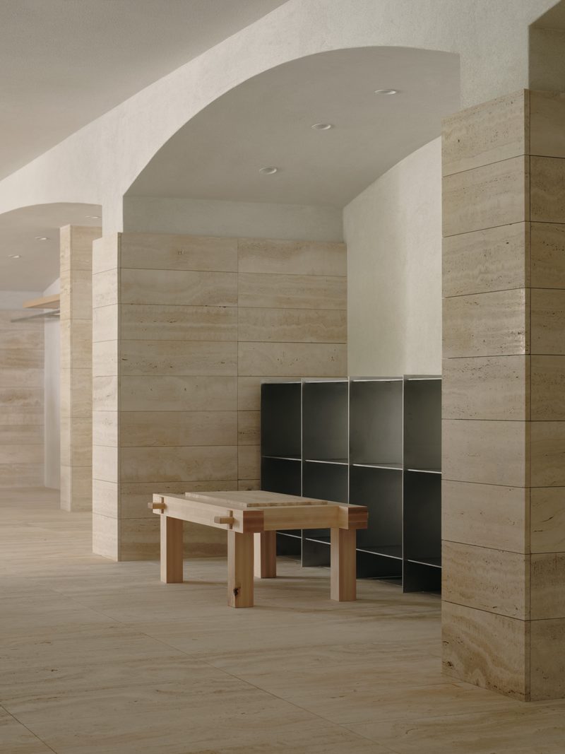 Arched travertine room with a timber bench and steel shelving