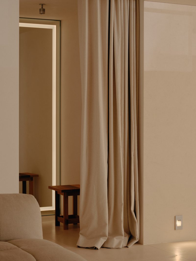 Floor-length linen curtains with a timber stool