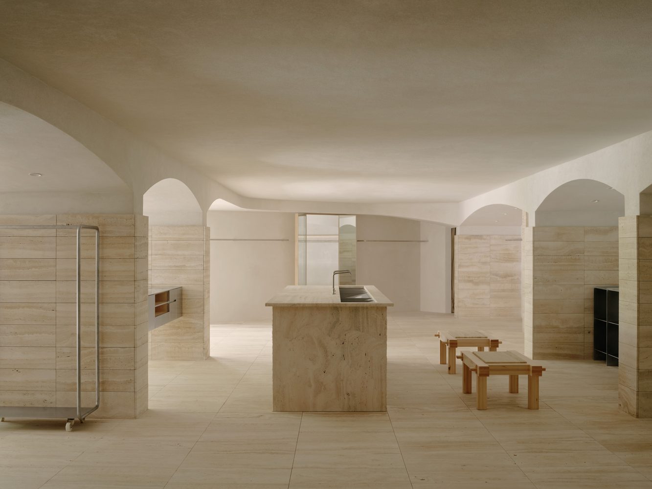 Travertine kitchen island beneath vaulted arches