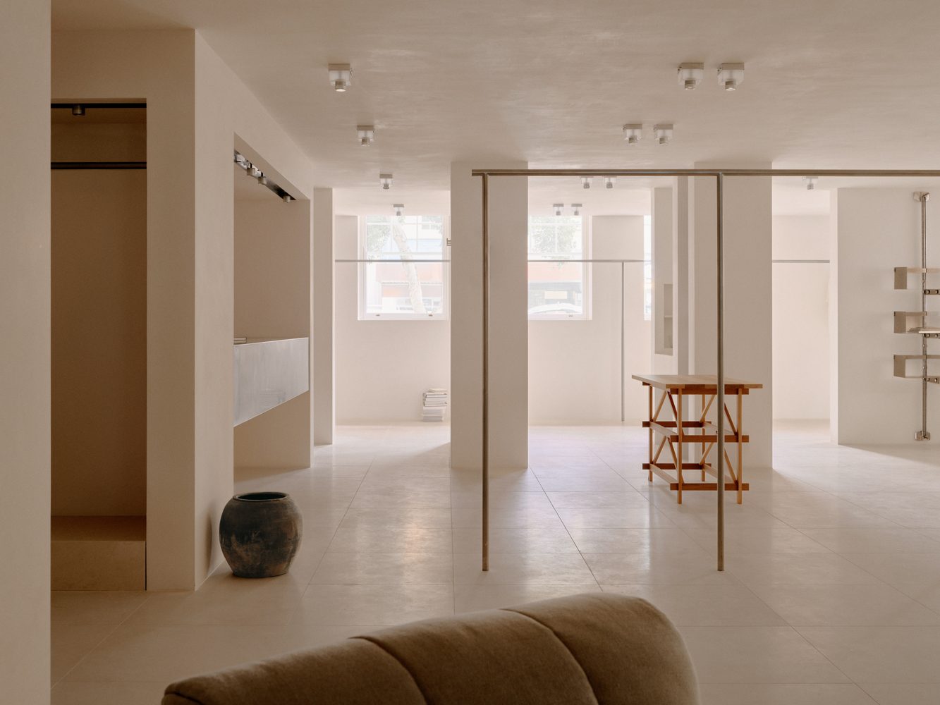Long white room with pendant lights and a stone vessel