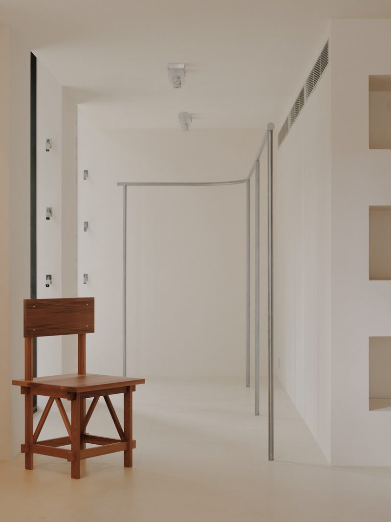 Timber chair in a white room with steel hanging rails